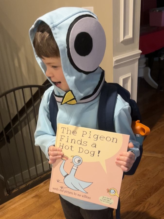Teddy in a homemade Pigeon costume holding a Mo Willems picture book